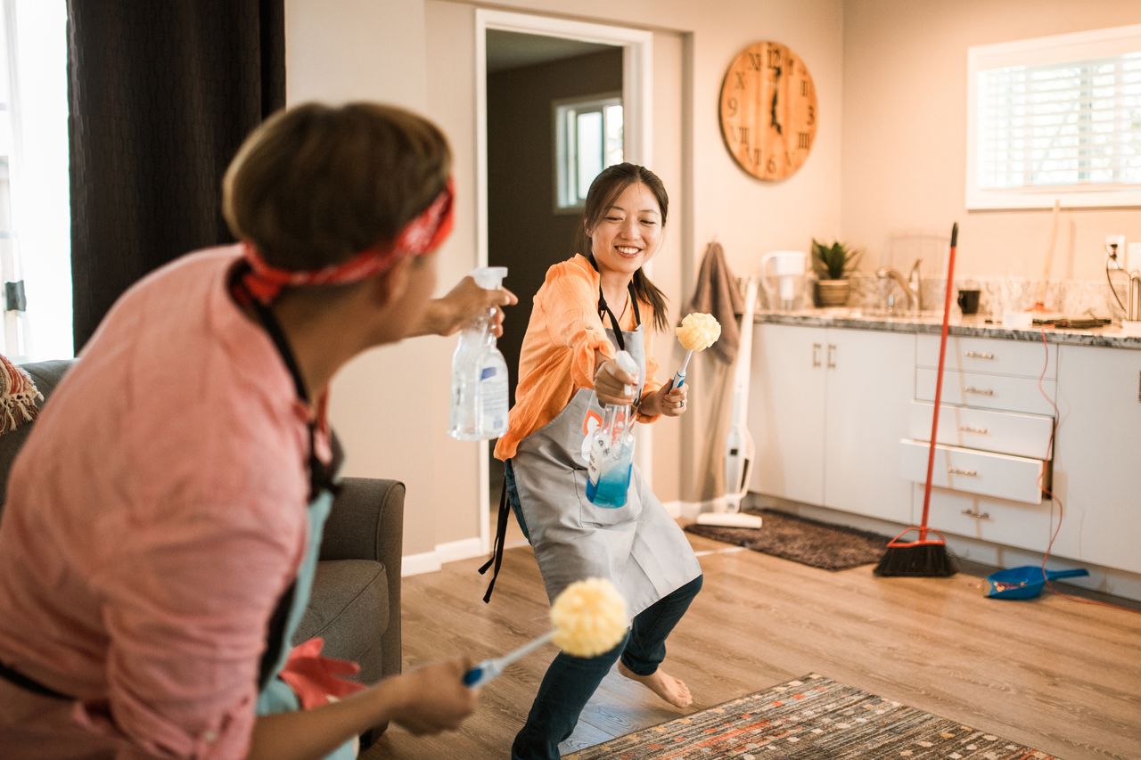 Un couple asiatique s’amuse en nettoyant sa maison, créant une ambiance joyeuse.